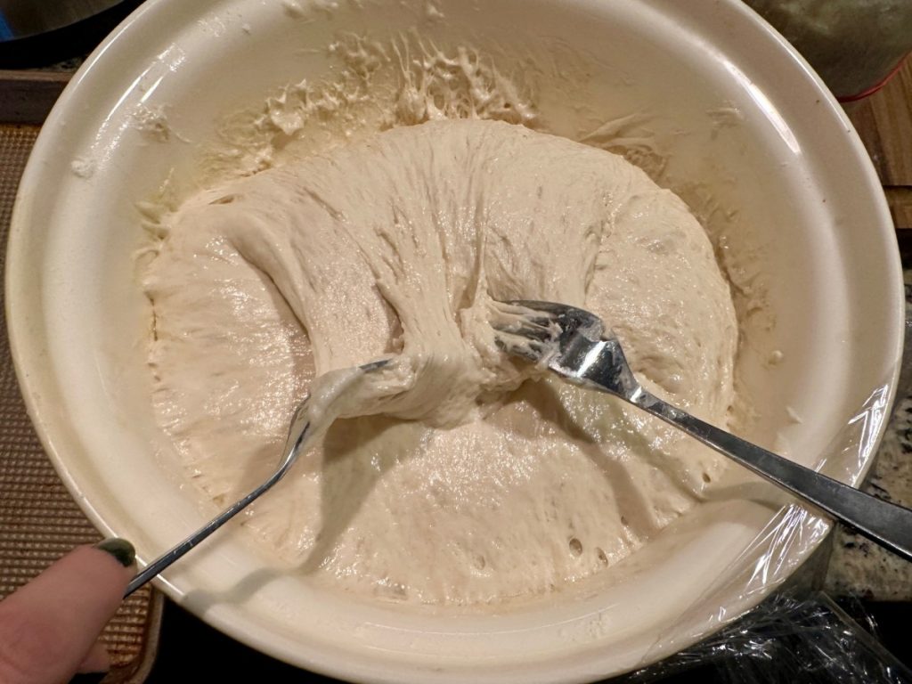 folding the focaccia dough with forks to gently deflate and shape 