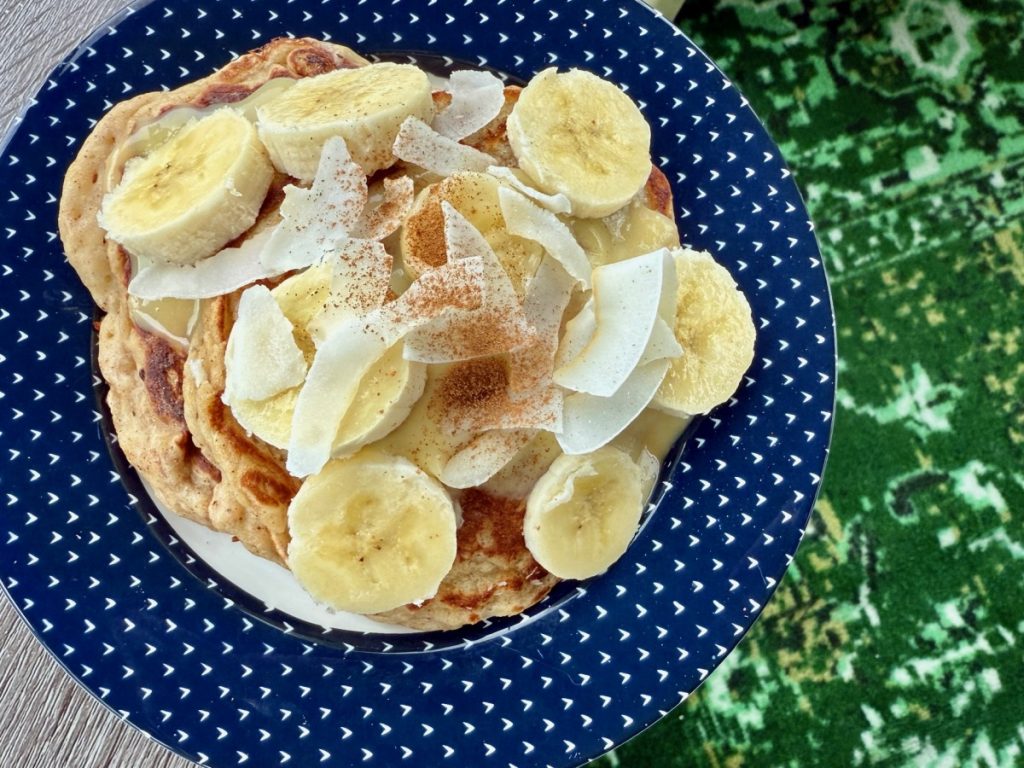 Easy Coconut Banana Pancakes (dairy-free) | These lightly-spiced coconut banana pancakes have a delightful tiki vibe, with subtle tropical flavors of coconut and banana that you can take over the top with some extra banana and pineapple topping!  These are an easy & delicious dairy-free brunch recipe as well.  
