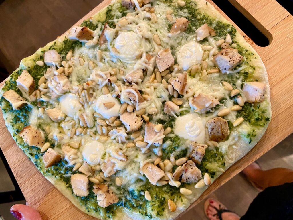 How to Make Grilled Pesto Pizza | Grilled pizza is one of the easiest & most delicious weeknight meals, and pesto pizza is one of my most popular pizza flavor combos.  I strongly believe in using fresh homemade pesto makes this taste so much better!  You can add chicken, pine nuts and more. or just have it be simple pesto and cheese. #grilledpizza #pesto #pizza