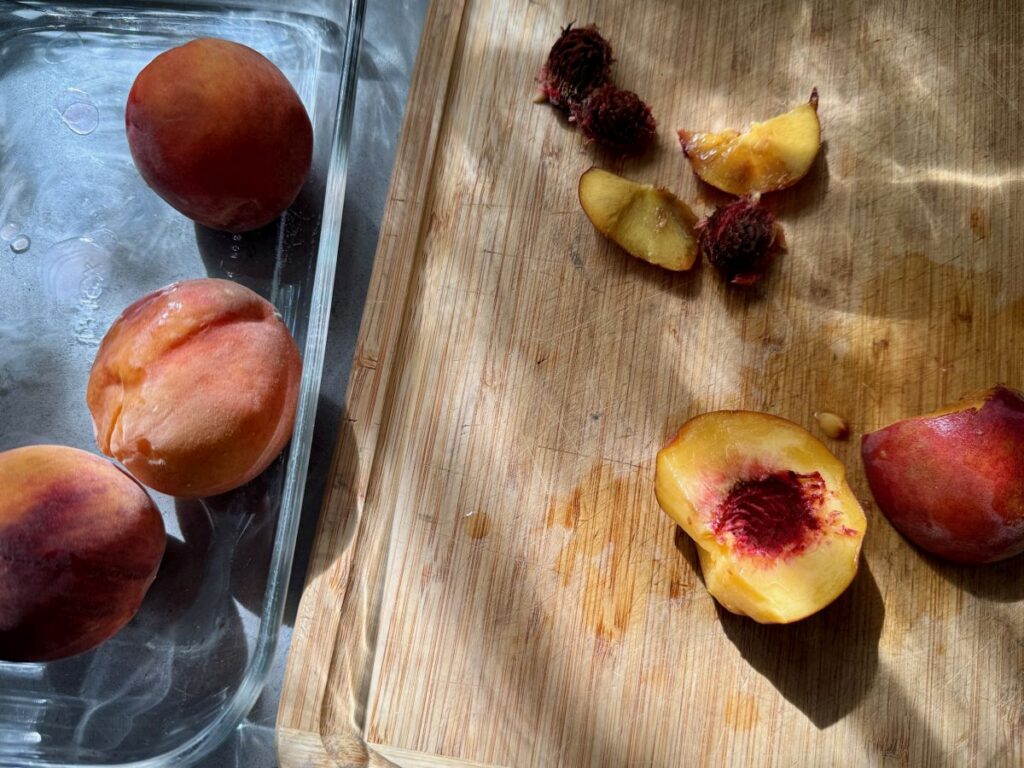 cutting up fresh ripe peaches on a wood cutting board with pretty sunlight